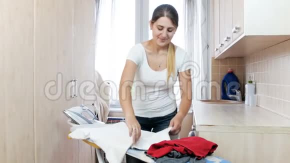 Bauitufl年轻女子在洗衣店熨衣服小心地把衣服叠起来视频的预览图