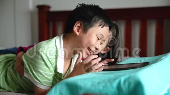 亚洲儿童使用数字平板电脑转移注意力亚洲儿童使用数字平板电脑快乐的姐姐微笑着为她的兄弟欢呼视频的预览图