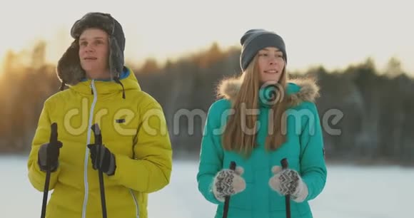 在冬天的森林里在日落时分情侣们滑雪环顾四周看看大自然的美丽和缓慢的景点视频的预览图