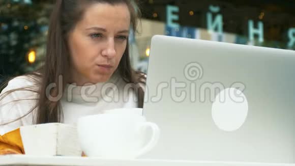女人在户外咖啡馆用笔记本电脑视频的预览图