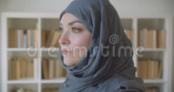 年轻的穆斯林迷人女商人戴着头巾的特写肖像看着镜头在图书馆里开心地微笑着视频的预览图