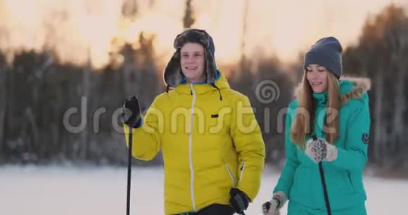 在日落时分的冬季森林里一男一女一滑雪看着大自然的美景和慢镜头视频的预览图
