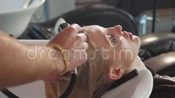 一位男造型师在一家现代美容店里给一个金发女人洗头视频的预览图