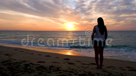 在海滩上欣赏风景优美的日出的女性剪影上放大视频的预览图