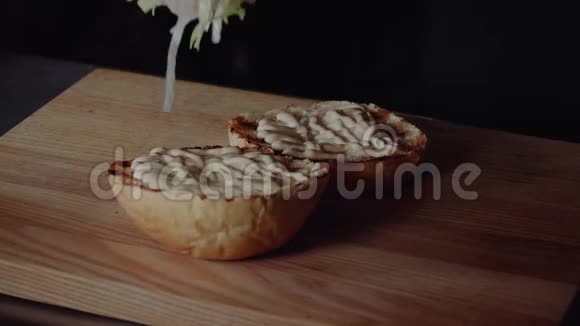 做汉堡的厨师在烤架上煎包子放生菜视频的预览图