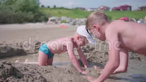 哥哥在海滩上和一个孩子玩做沙模视频的预览图