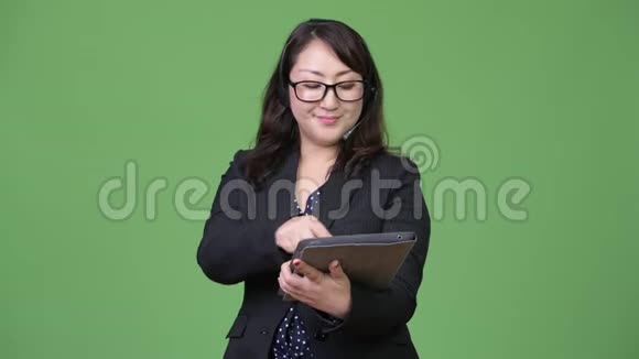 成熟美丽的亚洲女商人以呼叫中心代表的身份使用数码平板电脑视频的预览图