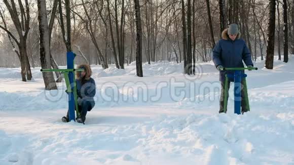 穿着蓝色夹克的男人和女人在冬季公园里从事模拟器前景视频的预览图