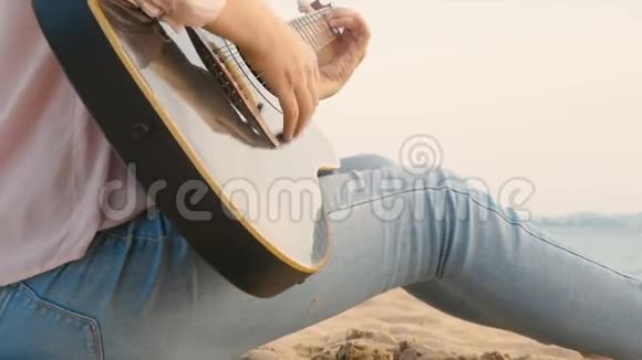 4k日落时分长发女子在沙滩上用轻柔的风弹吉他感觉轻松视频的预览图