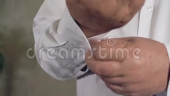 成熟男人的手扣在白色衬衫的袖子上视频的预览图