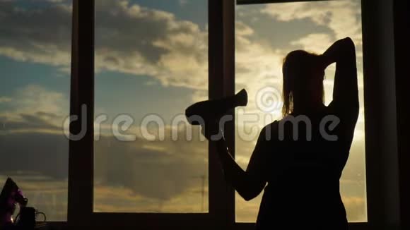 一位中年妇女在日落时分烘干吹风机她唱歌跳舞视频的预览图