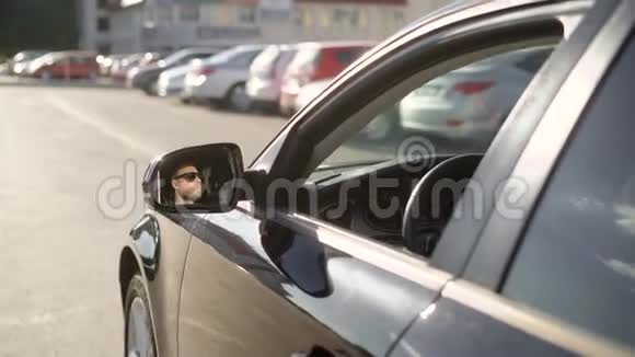 在阳光明媚的日子里人们在城市道路上开着一辆大汽车从外面看他的脸在后视镜里反光视频的预览图