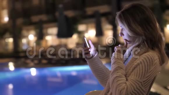 优雅美丽的女孩晚上用手机视频的预览图