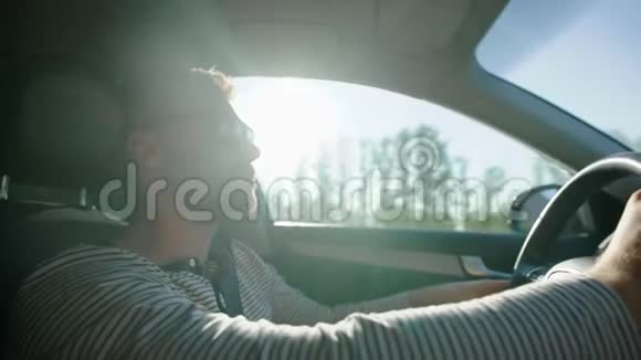 在阳光明媚的日子里孤独的人正在乡下开车戴着太阳镜拿着方向盘仰视着视频的预览图