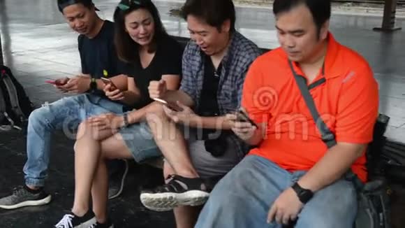 一群青少年坐在长椅上使用他们的智能手机视频的预览图