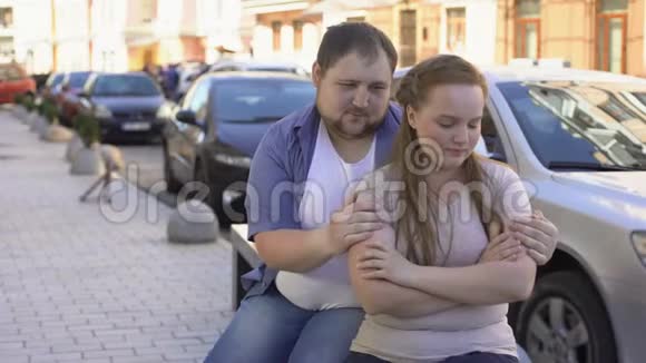 内疚的男人和心烦意乱的女朋友在一起坐在街头的长凳上吵架视频的预览图