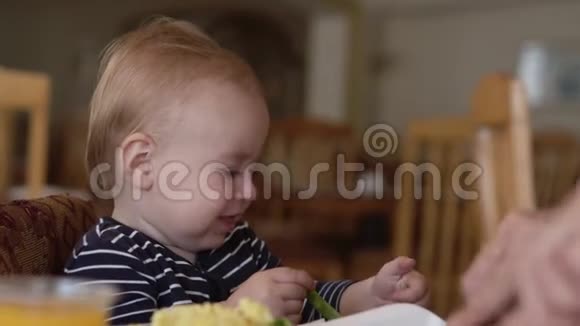 小可爱的宝宝坐在婴儿椅上吃食物视频的预览图