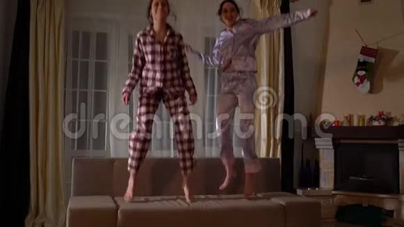 快乐的姐妹双胞胎在帕詹姆斯跳在沙发上舒适的客厅和乐趣就像在童年关系视频的预览图