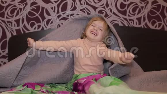 快乐的小女孩躲在毯子下面看电视儿童睡眠概念视频的预览图
