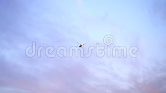 蓝天云彩和粉红色的日落一架红色的直升机在天空中飞翔视频的预览图