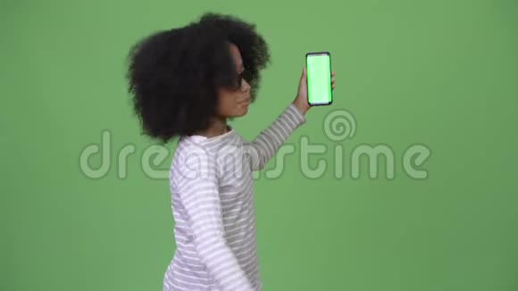 年轻可爱的非洲女孩留着非洲头发带着手机竖起大拇指视频的预览图