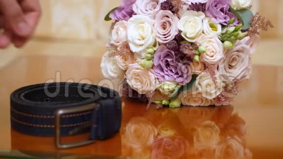 特写美丽的婚礼花束玫瑰乳制品白色和丁香附近男性手拿皮带婚礼视频的预览图