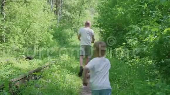 孩子们在公园里玩两个孩子在森林里沿着一条狭窄的小路跑户外娱乐视频的预览图