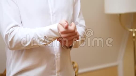 特写男性双手扣紧白色衬衫袖口上的纽扣视频的预览图