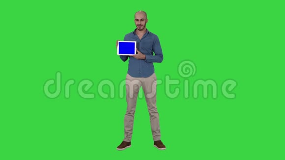微笑休闲男子呈现一个平板电脑与空白屏幕上的绿色屏幕铬键视频的预览图