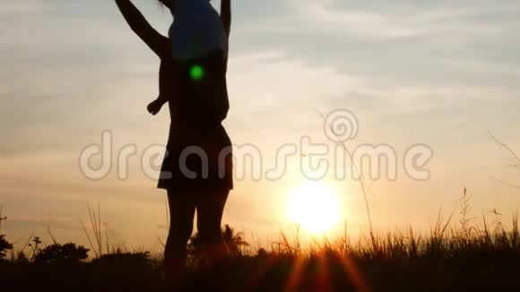 幸福的母女在美丽的夕阳背景下玩纸飞机的剪影视频的预览图