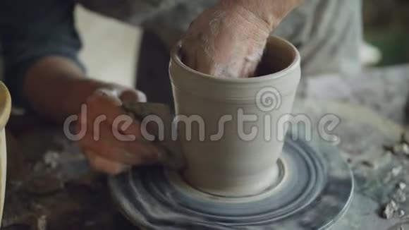在家庭工作室用专业的纺抛轮工具陶工双手平滑成型锅的特写镜头视频的预览图
