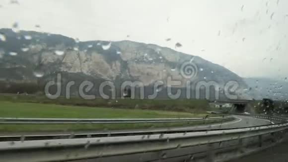 雨天汽车沿着田野和山丘在农村的大路上行驶视频的预览图