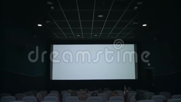 观众坐在白色屏幕前人们在电影院鼓掌视频的预览图