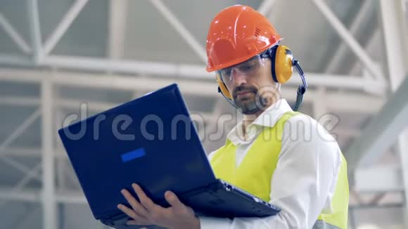 这位工厂的男员工正在用他的笔记本电脑工作环顾四周视频的预览图