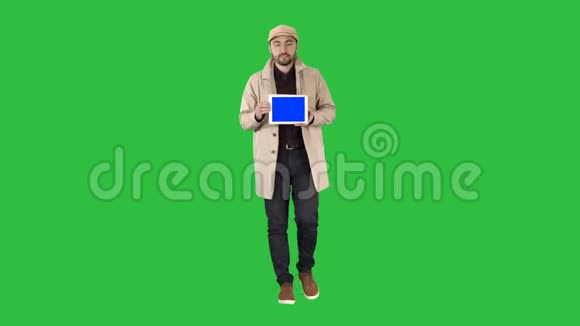 有吸引力的人拿着平板电脑与蓝色的关键屏幕模型在绿色屏幕铬键视频的预览图