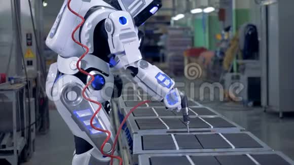 类似人类的机器人正在工厂的一个单位里用钻头工作视频的预览图