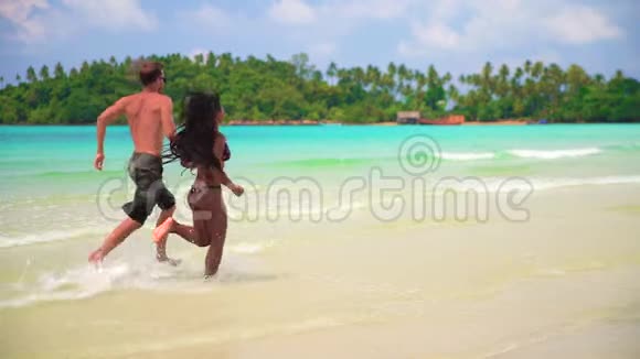 慢动作年轻夫妇在沙滩上冲浪视频的预览图