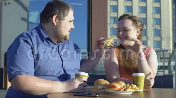 喜欢吃汉堡的快乐女人在户外咖啡馆里吃快餐视频的预览图