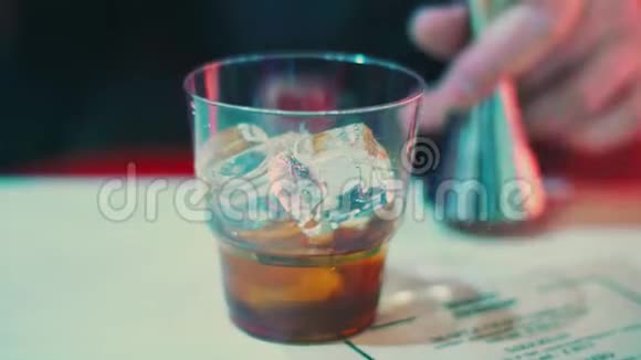 酒吧老板用冰块把酒精饮料倒入杯子里啤酒制造威士忌视频的预览图