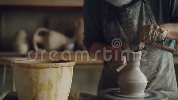 老工匠正在用专业的工具在陶工车轮上制造陶瓷罐有手工盆的工作场所视频的预览图