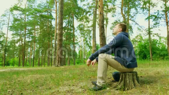 人休息坐在森林里的树桩上放松一下视频的预览图