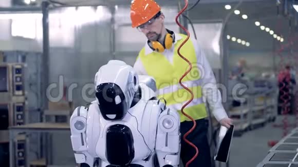 类似人类的机器人在接到工厂工人的相应命令后开始用钻头工作视频的预览图