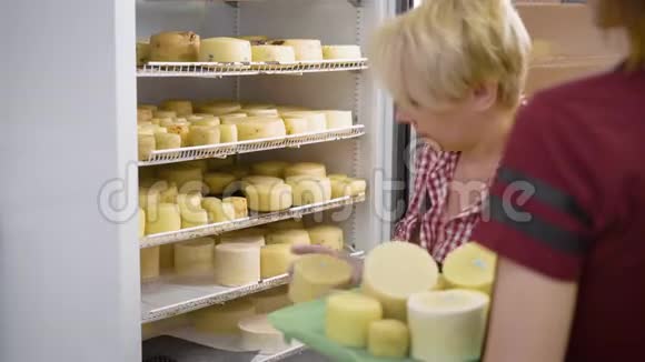 女工人把煮好的奶酪头放进巨大的工业冰箱里放在奶酪加工厂里视频的预览图