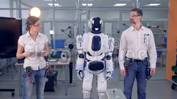 男工程师和机器人在女工程师的监督下同步移动视频的预览图