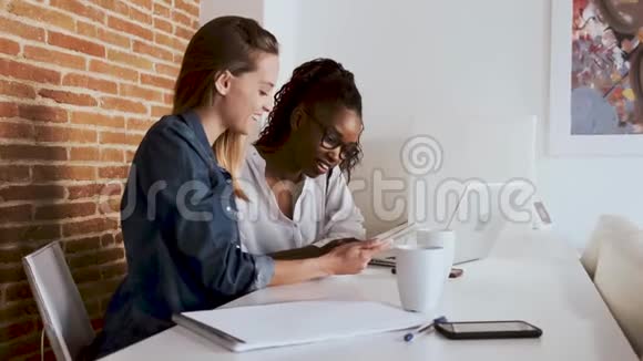 两个年轻漂亮的女商人在办公室里和数码平板电脑一起工作视频的预览图