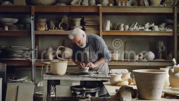 经验丰富的陶工正在车间用陶工车轮上的粘土制造器皿生产食品手工制作视频的预览图
