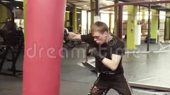 一个年轻的拳击手在体育馆里打了一个拳击包视频的预览图