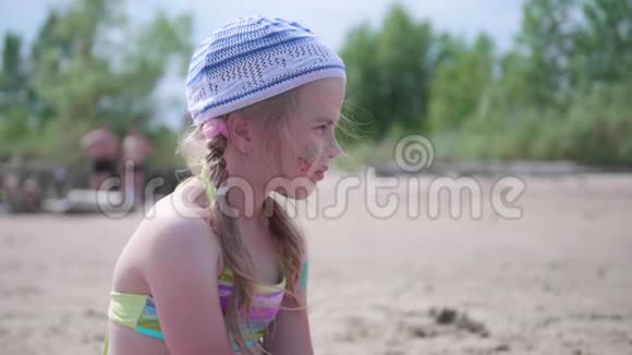小女孩坐在沙滩上炎炎夏日小心翼翼若有所思的望向远方视频的预览图