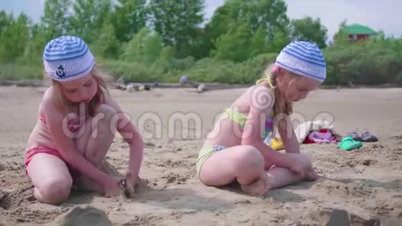 两个女孩在海滩上玩耍做沙子夏日炎炎海上家庭假日视频的预览图