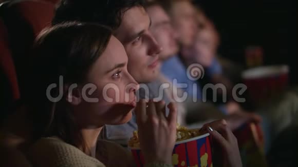 年轻夫妇吃一盒爆米花情侣看电影视频的预览图